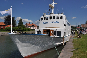 A white tour boat moored at one side of a canal.